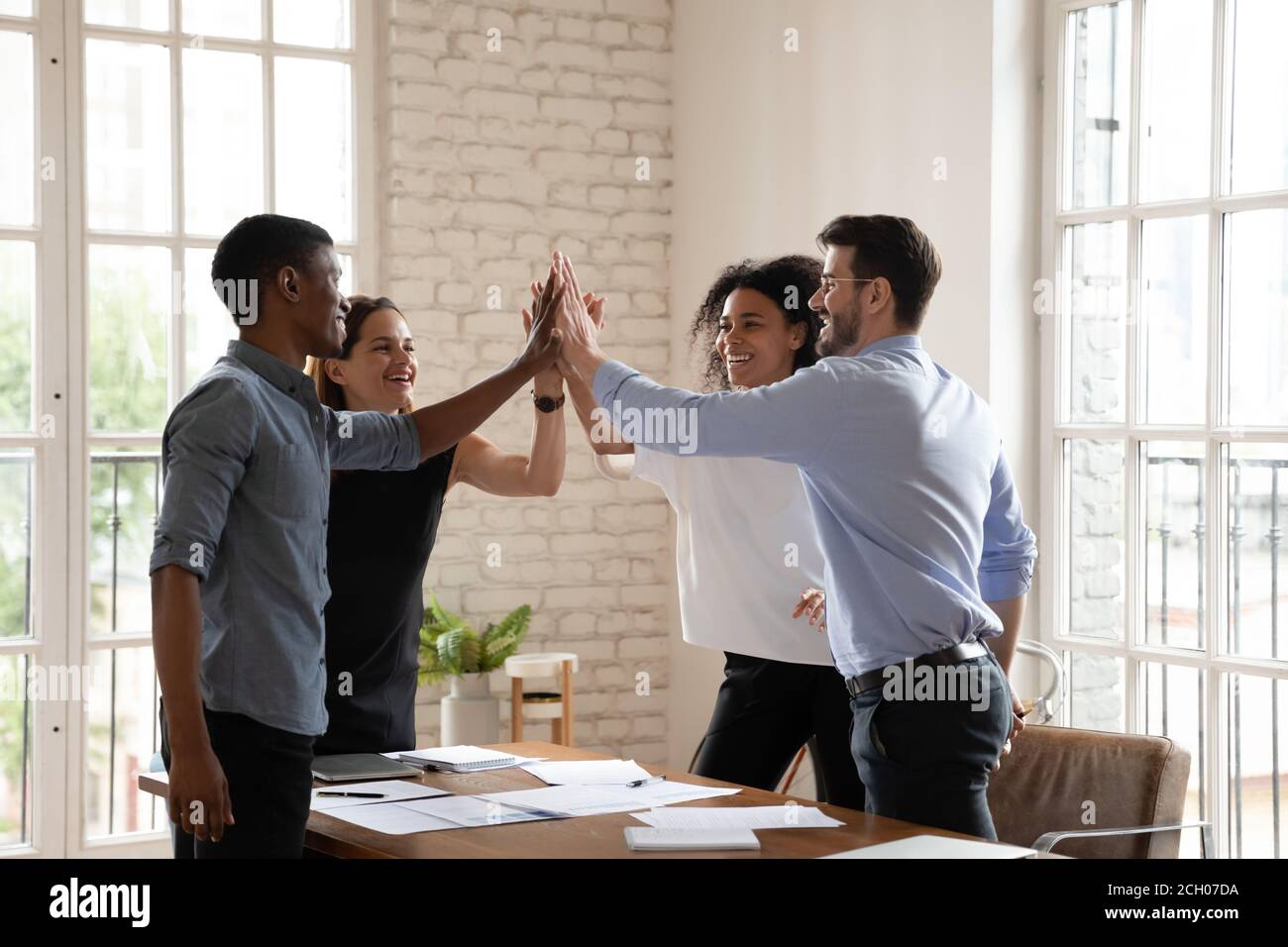 Excited diverse coworkers give high five celebrate success Stock Photo ...