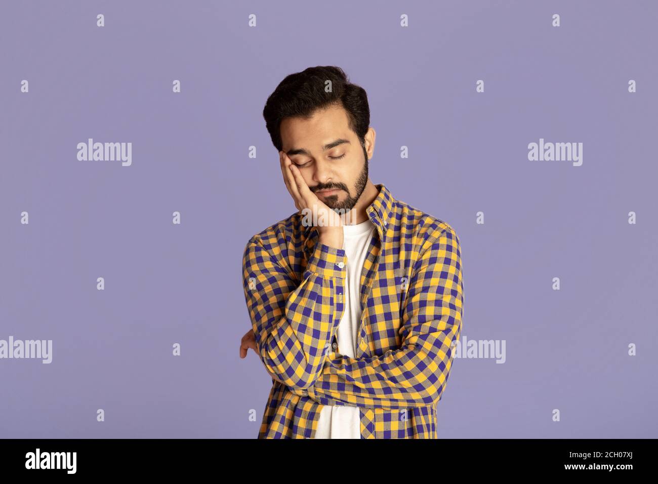 Tired Indian guy sleeping after overworking on lilac background Stock Photo