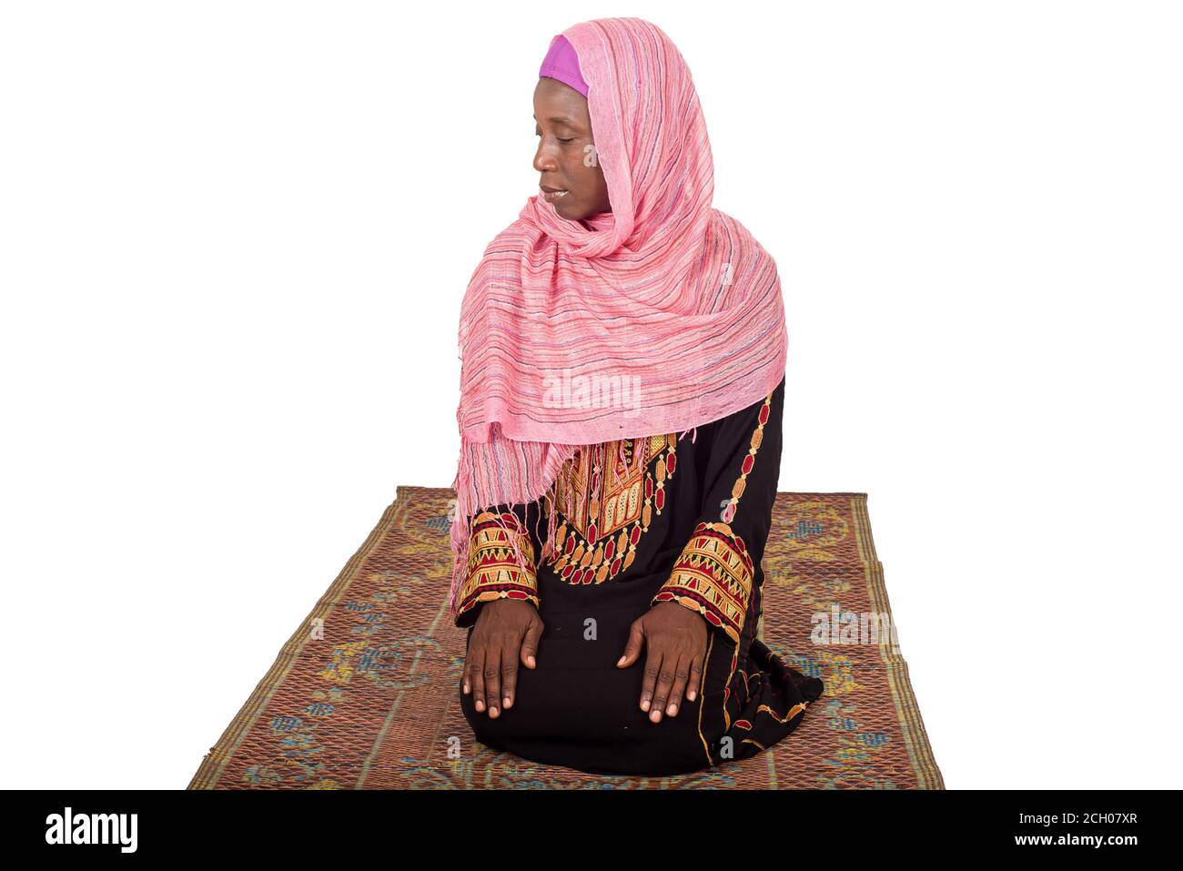 young woman on her knees on a veiled head mat and praying. Stock Photo