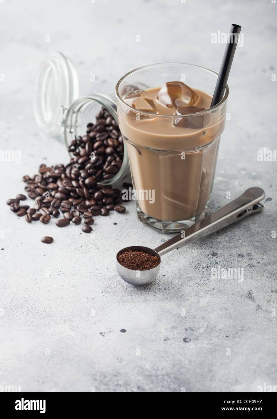 https://c8.alamy.com/comp/2CH09HY/glass-of-iced-coffee-with-milk-with-jar-of-coffee-beans-and-silver-scoop-on-light-table-background-2CH09HY.jpg