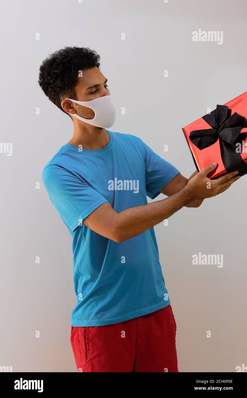 Man black with pandemic mask holding a gift isolated white background ...