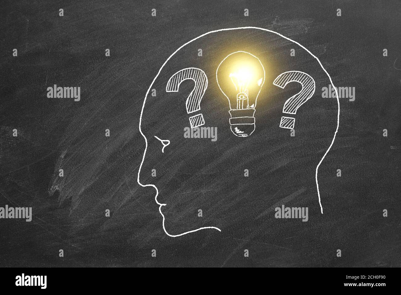 The question marks in human head turns into a light bulbs. Chalk drawing on a blackboard. Stock Photo