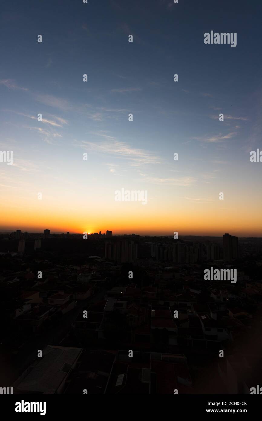 Rising sun with silhouette of buildings on city skyline Stock Photo