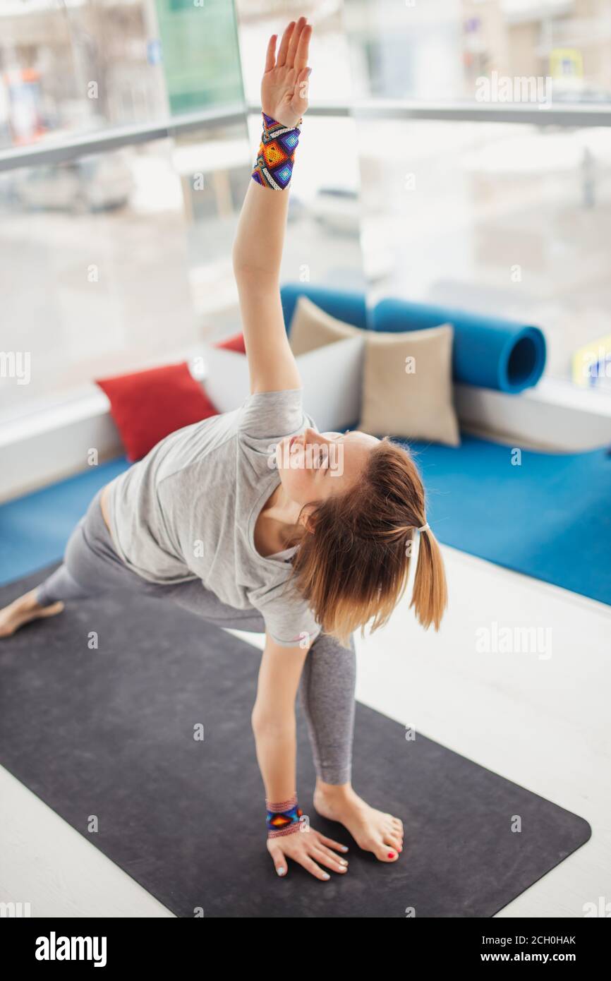 Young flexible woman practicing yoga, stretching in Utthita Trikonasana ...