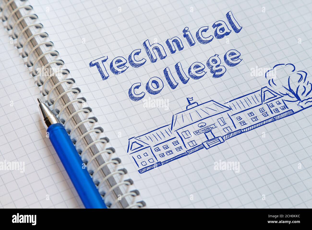 Notebook with a spiral in a cage and blue pen on it. On the left page drawn the school and lettering Technical college Stock Photo
