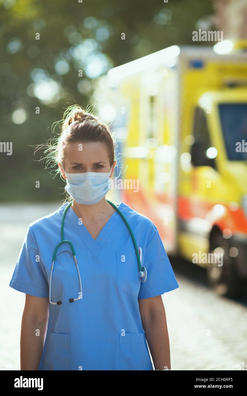 coronavirus pandemic. modern medical doctor woman in uniform with stethoscope and medical mask outside near ambulance. Stock Photo
