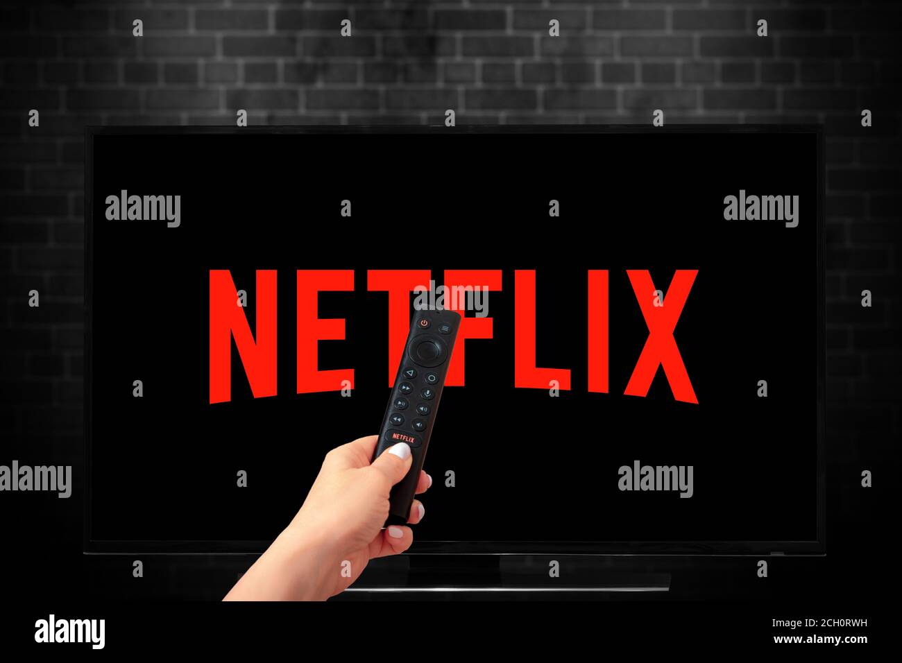 Close up of Nvidia Sheild TV Remote in Hand and TV Screen with Netflix Logo, Netflix is a well known global provider of streaming movies and TV series Stock Photo