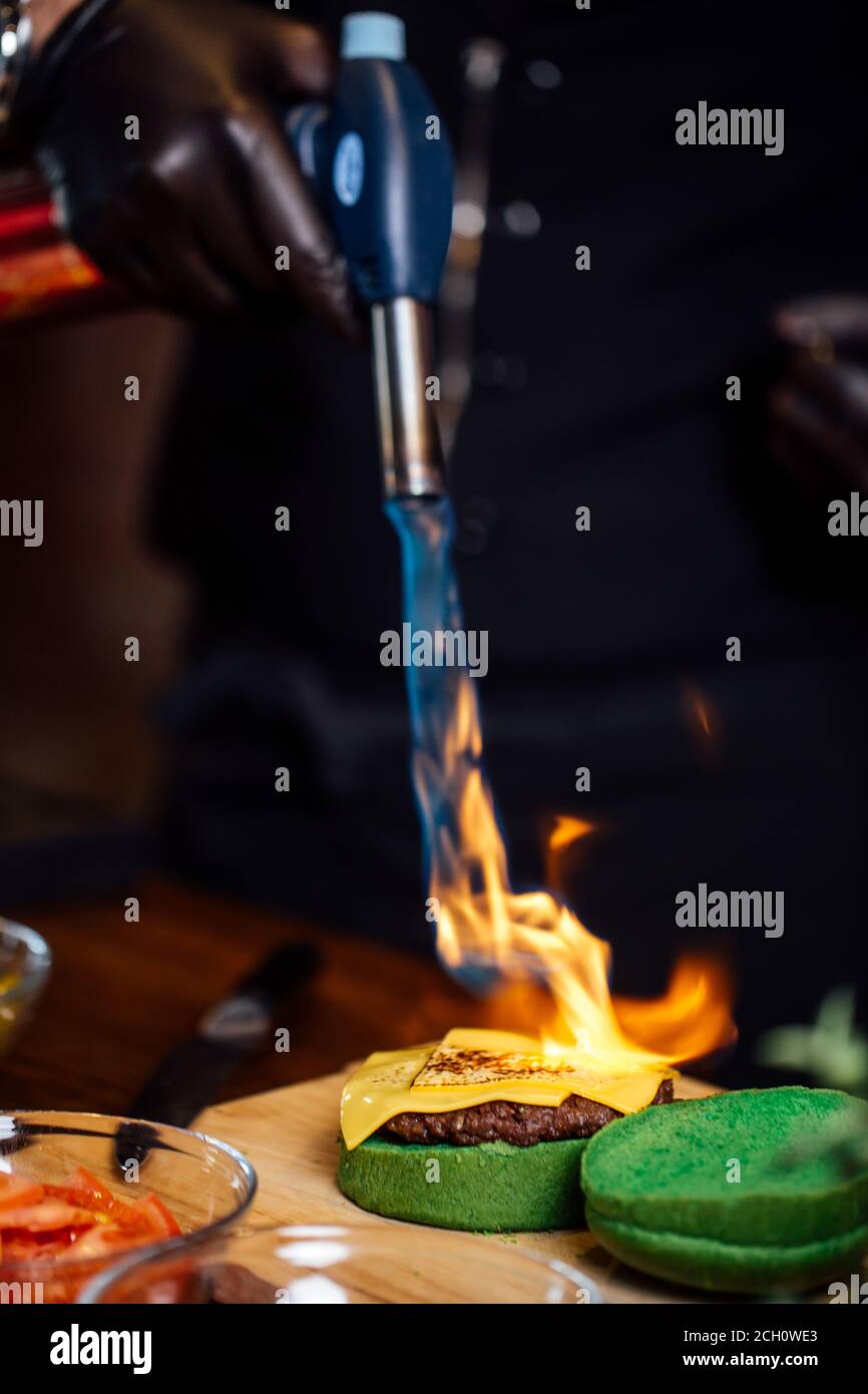 https://c8.alamy.com/comp/2CH0WE3/chef-making-beef-burgers-melting-cheese-on-burger-bun-with-culinary-burner-for-burgers-at-restaurant-kitchen-2CH0WE3.jpg