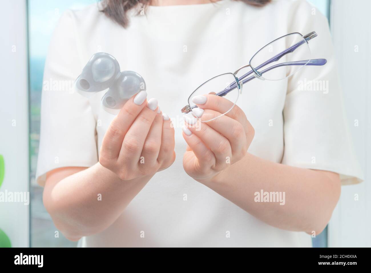 the woman holds glasses in one hand and one-day contact lenses in the other. myopia and eyesight, problem with vision concept Stock Photo