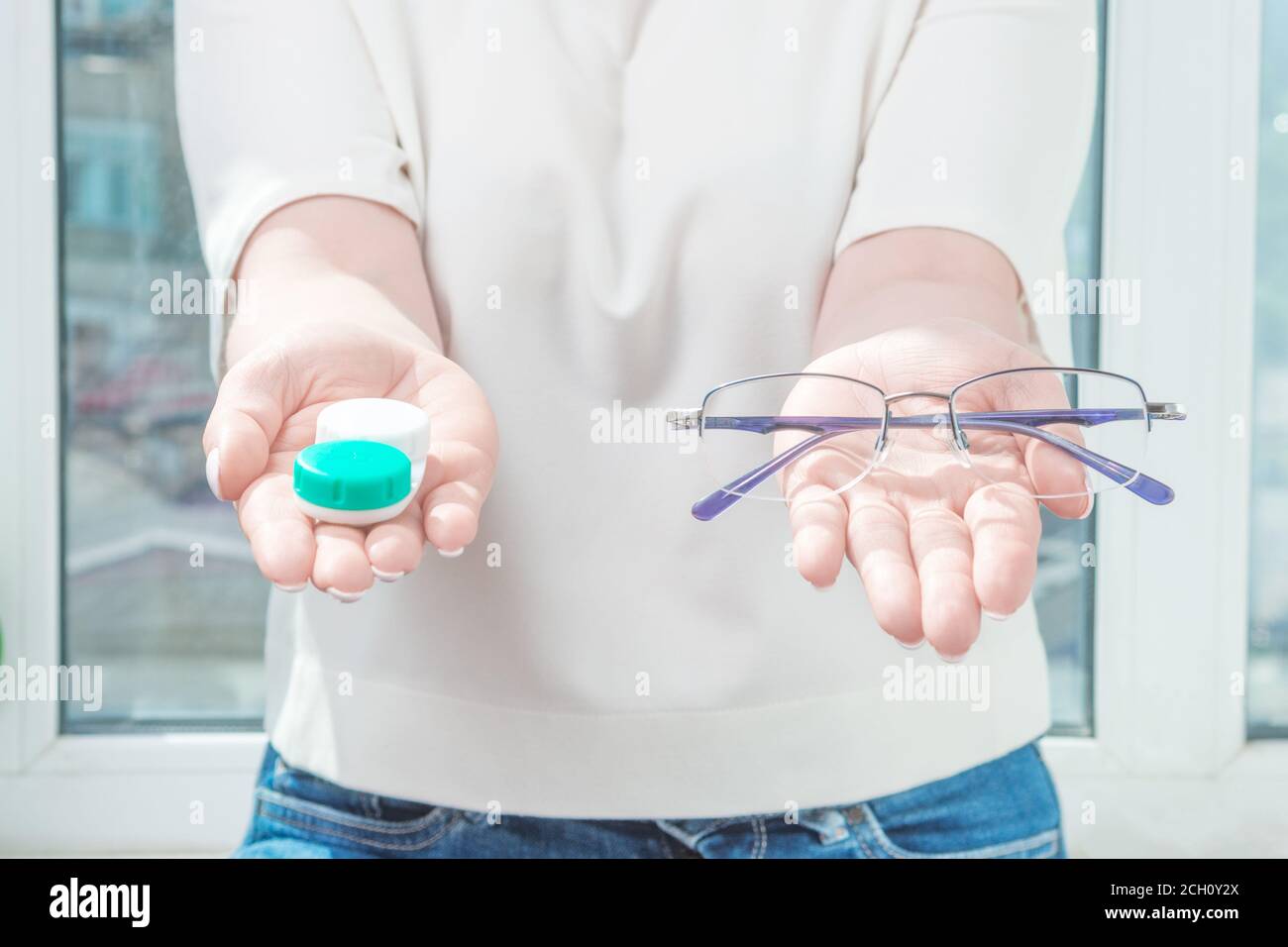 the woman holds glasses in one hand and one-day contact lenses in the other. myopia and eyesight, problem with vision concept Stock Photo