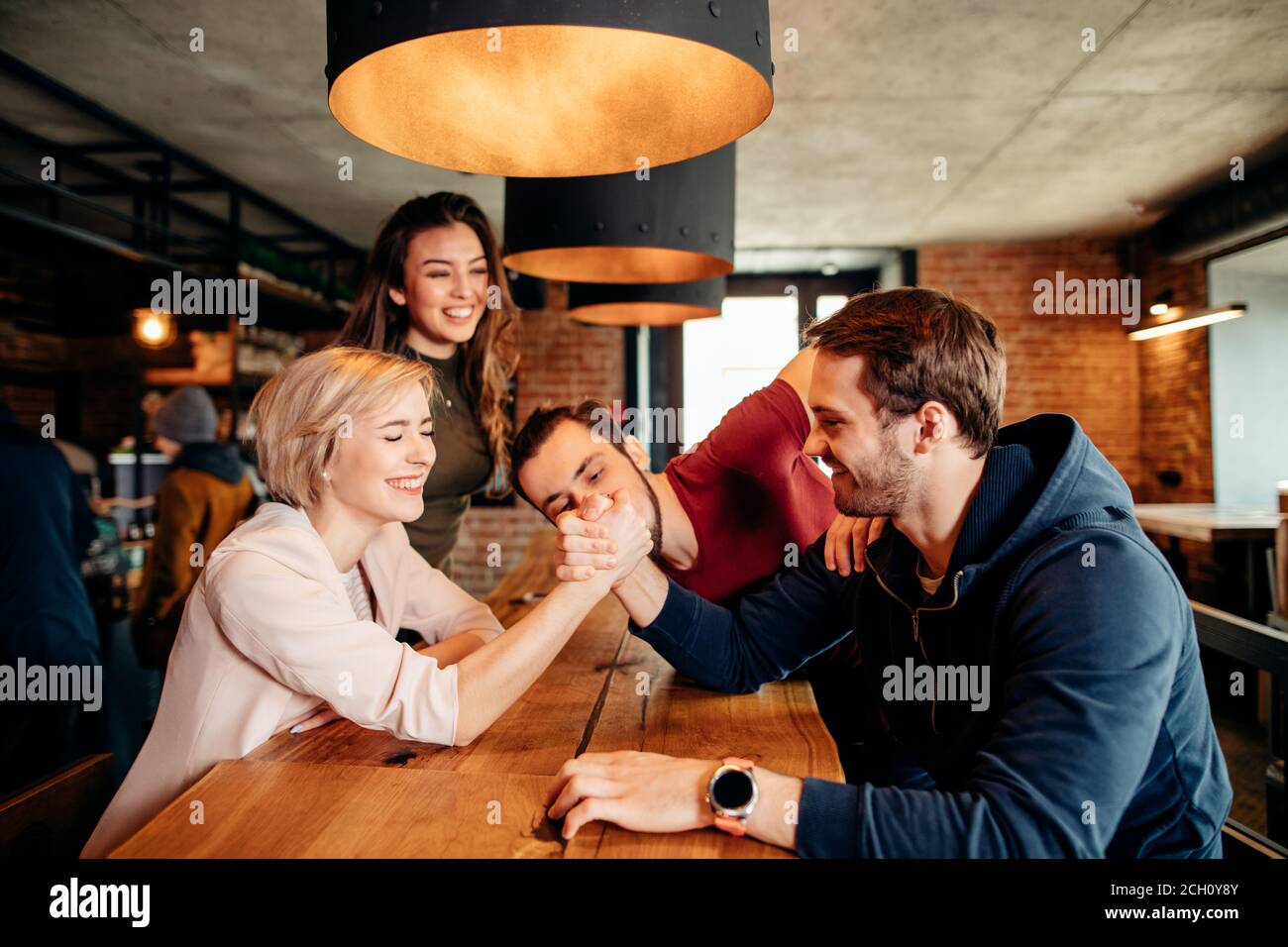Young attractive women girl friends and their new male friends playing,  wrestling and smiling while spending time together at trendy pub. Fun,  holiday Stock Photo - Alamy