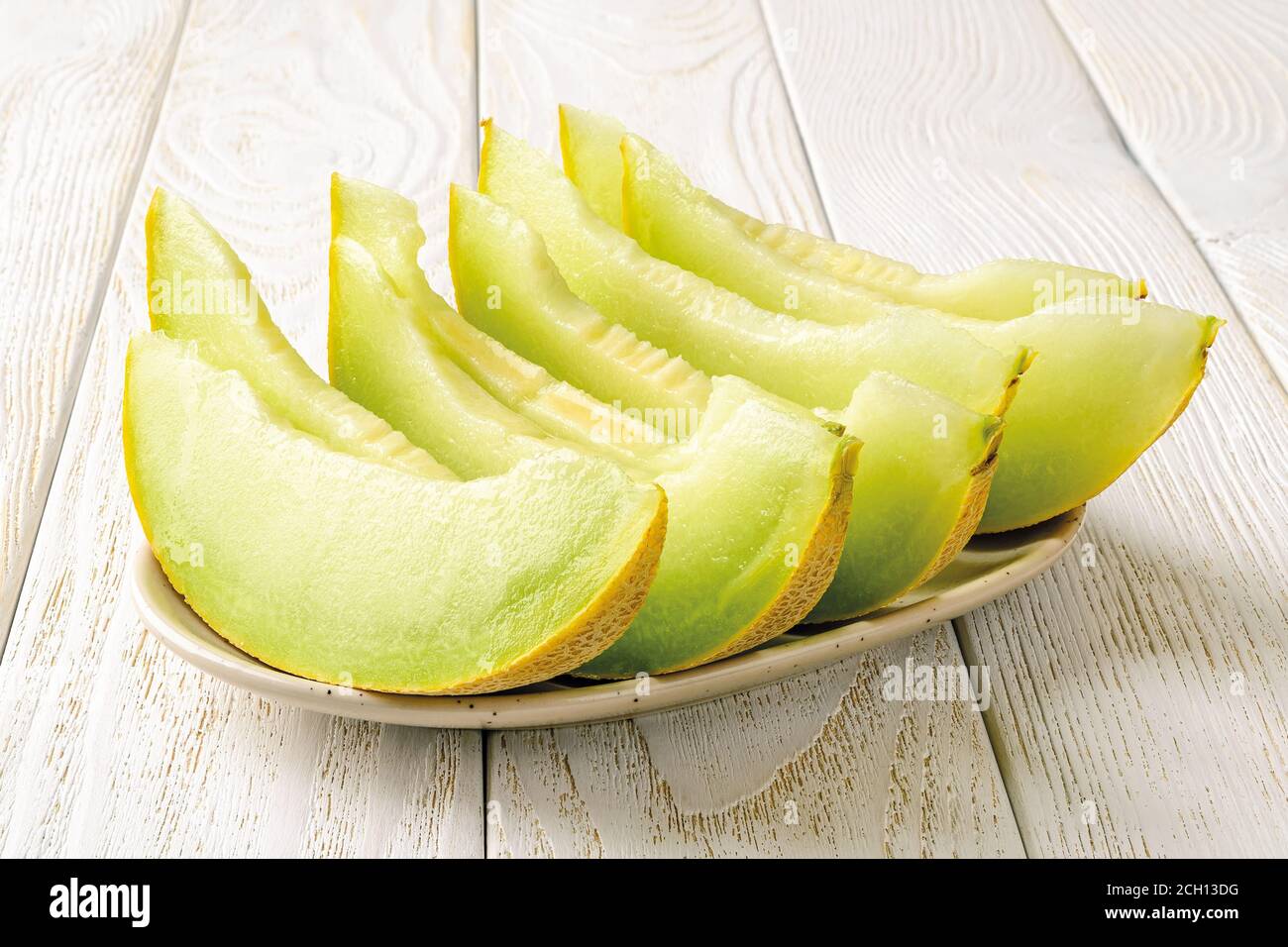 Slices of sweet juicy galia melon with green pulp on a plate over white