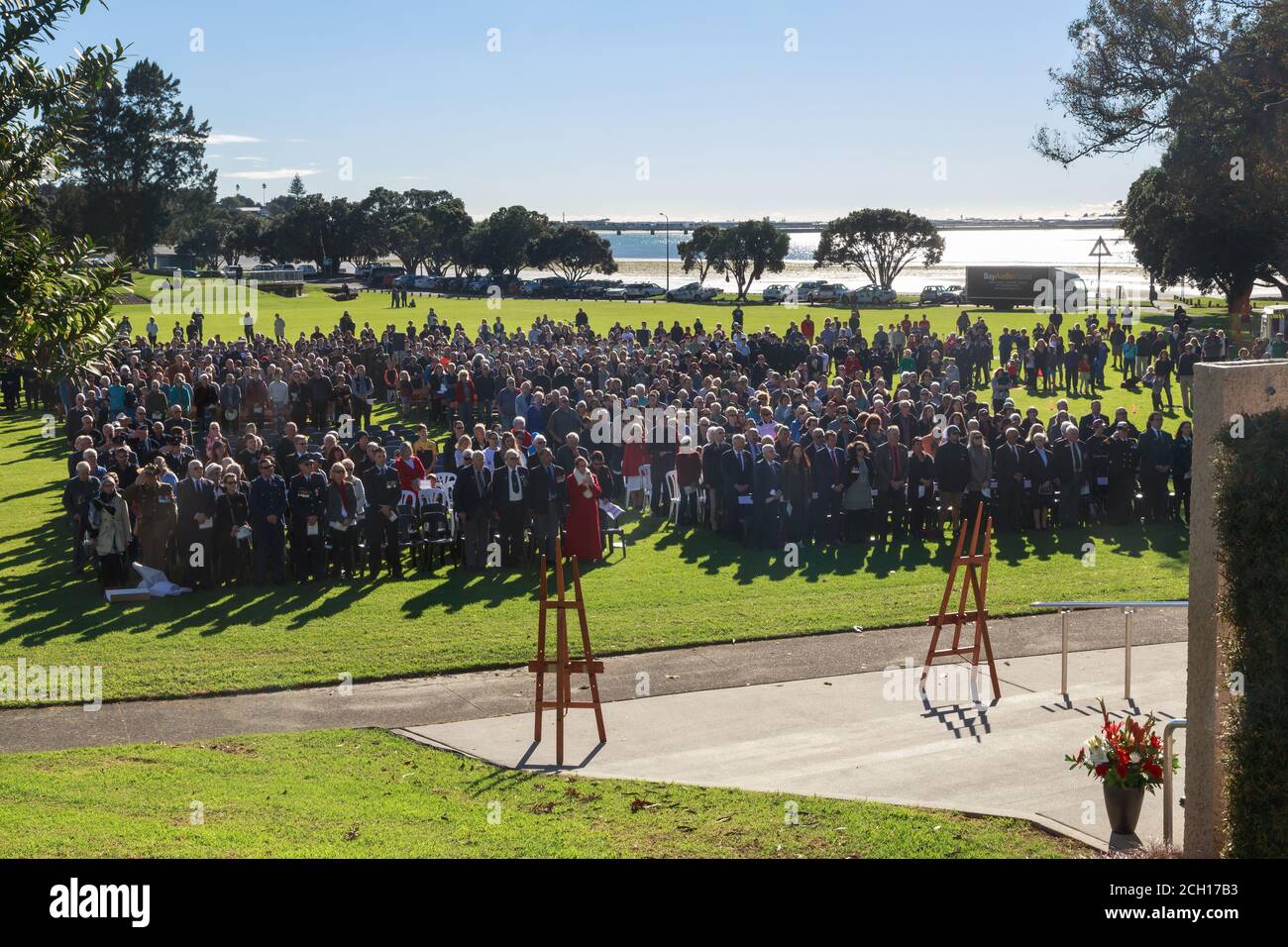 Anzac Day services in Tauranga, New Zealand. A large crowd rises for the national anthem in Memorial Park. April 25 2018 Stock Photo