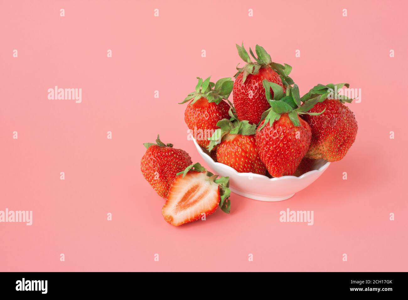 ripe red strawberries in a bowl on pink background. Heap of fresh strawberries in bowl. Fresh ripe delicious strawberries in a white bowl on pink back Stock Photo