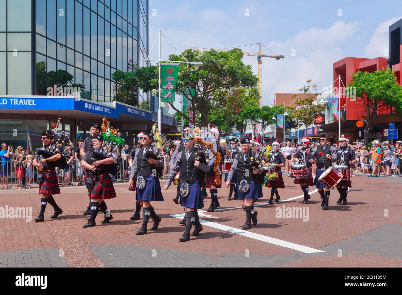 A Scottish pipe and drum band, with tinsel on their bagpipes, marching in a Christmas parade. Tauranga, New Zealand, November 30 2019 Stock Photo