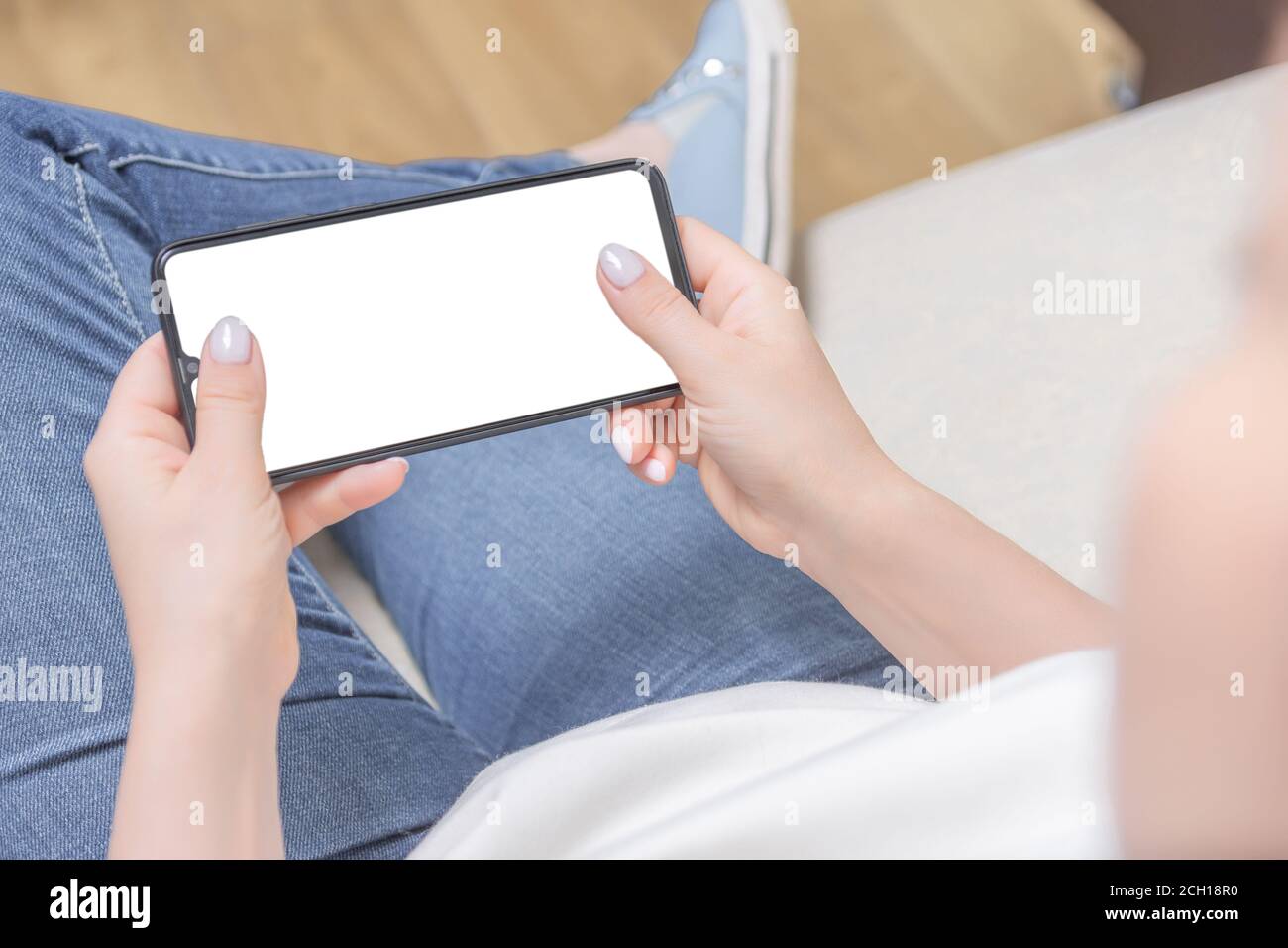 Mockup image of woman's hands holding white mobile phone with blank screen in horizontal position in horizontal position. Mockup cell phone. Top view. Stock Photo