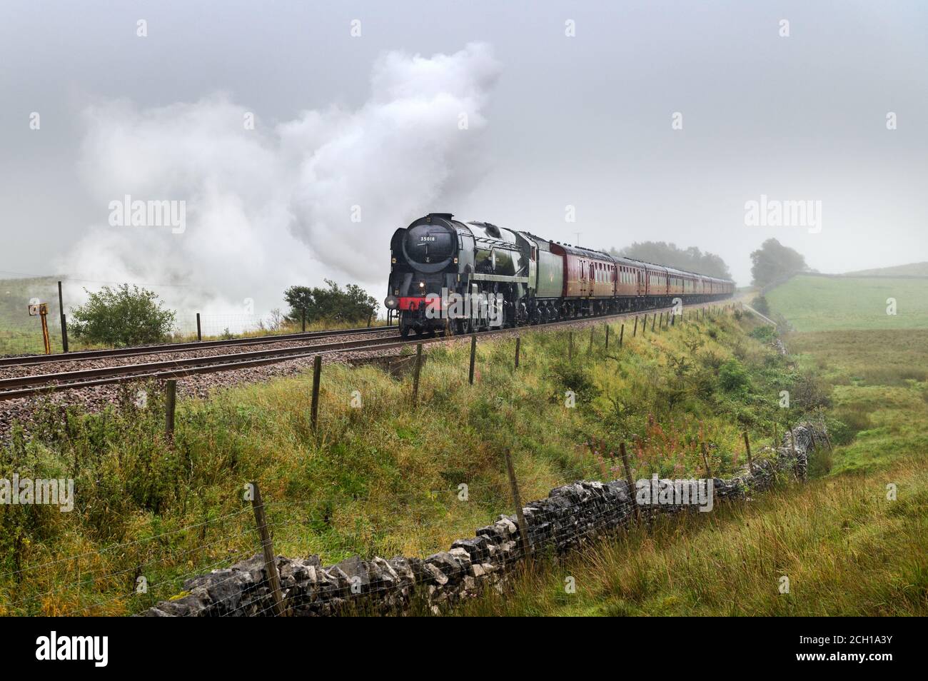 Steam loco 'British India Line' hauls 'The Dalesman' train on a wet and misty day. Seen at Selside, Ribblesdale, Yorkshire Dales National Park, UK Stock Photo
