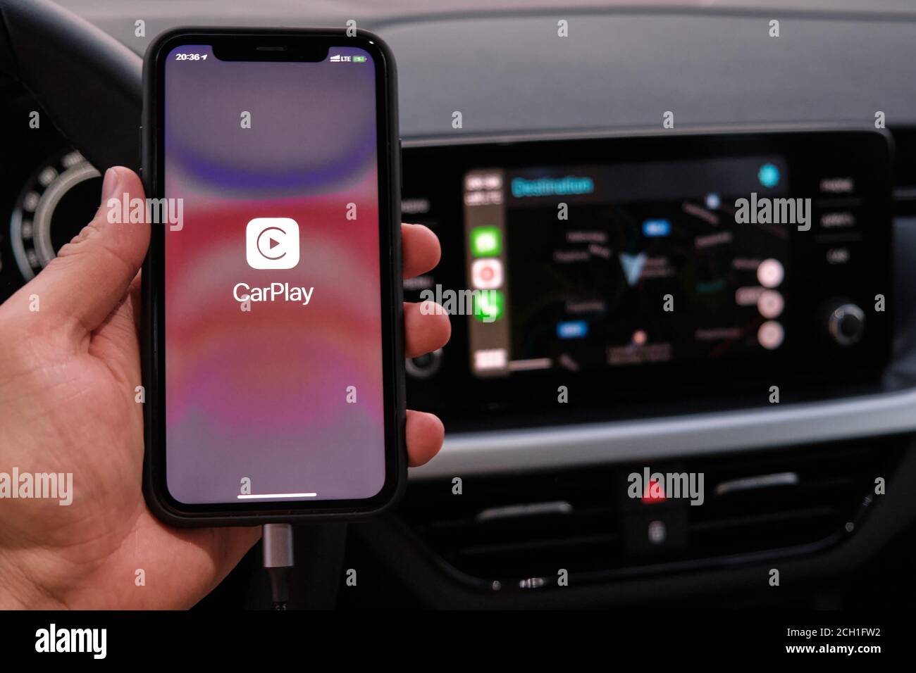 Closeup mans hand holding Iphone with Apple carplay logo on the screen