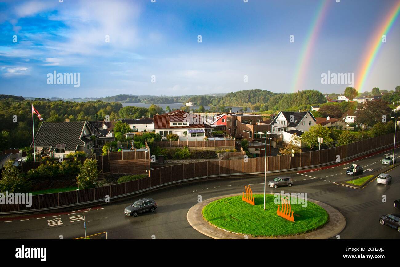Double Rainbow Over European Town with Roundabout and cars in foreground - Stavanger Norway Stock Photo