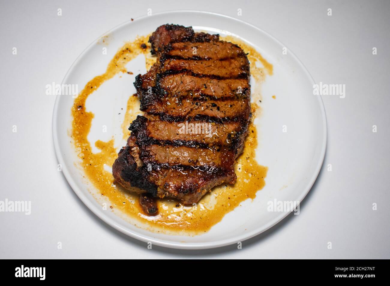 A Perfectly Cooked Steak With Grill Lines Plated on a Pure White