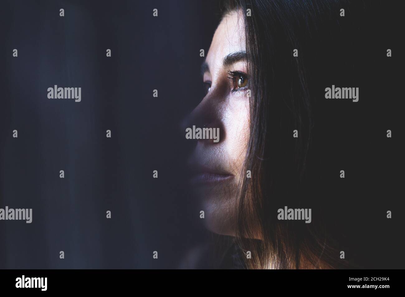 Young attractive woman with long hair, looking outside, lonely mood. Stock Photo
