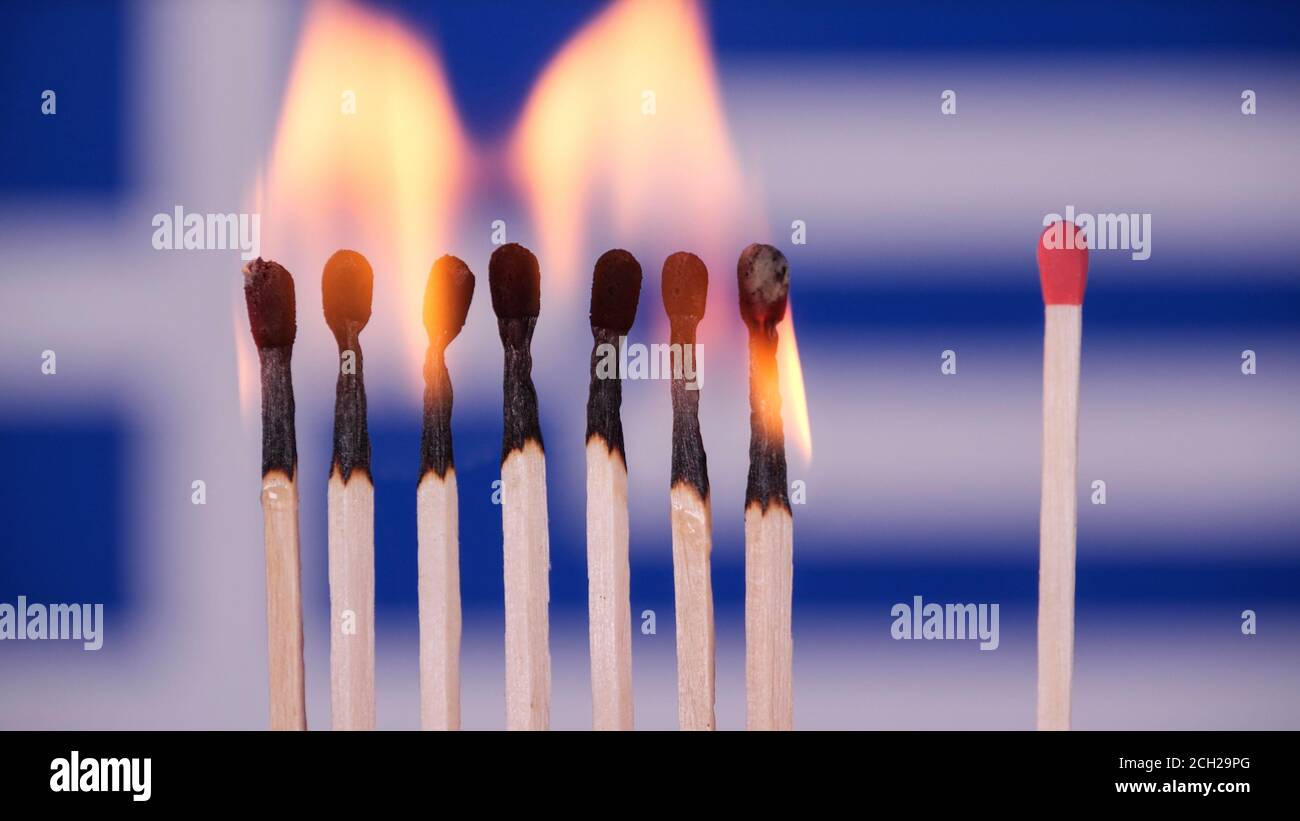 Coronavirus outbreak, social distancing concept. Burning matches on Greece flag background. Concept: spreading virus mechanism. COVID-19 Stock Photo