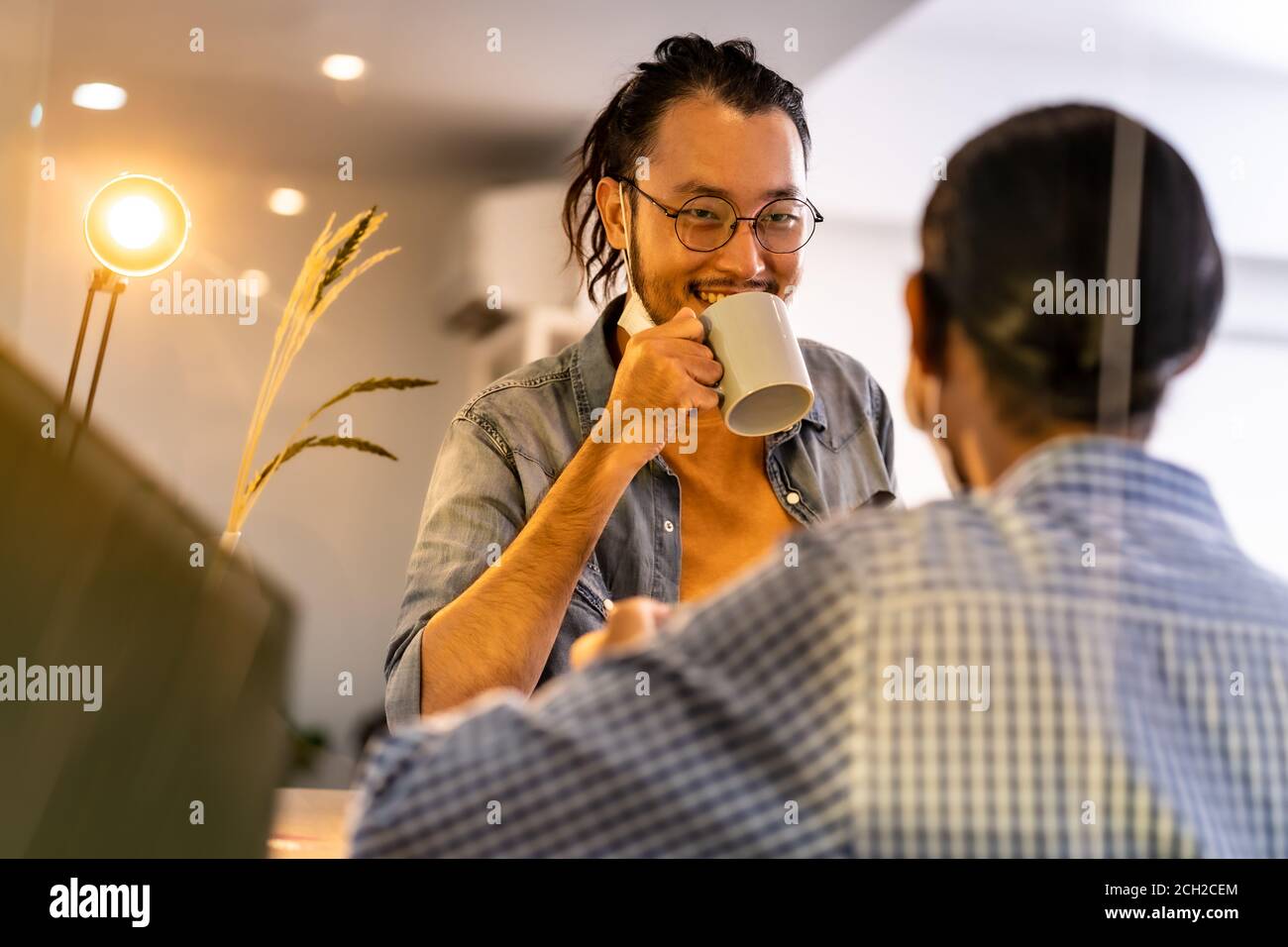 Two asian businessmen workers talking and discussion while coffee break bar at common zone of office. Office life concept. Stock Photo