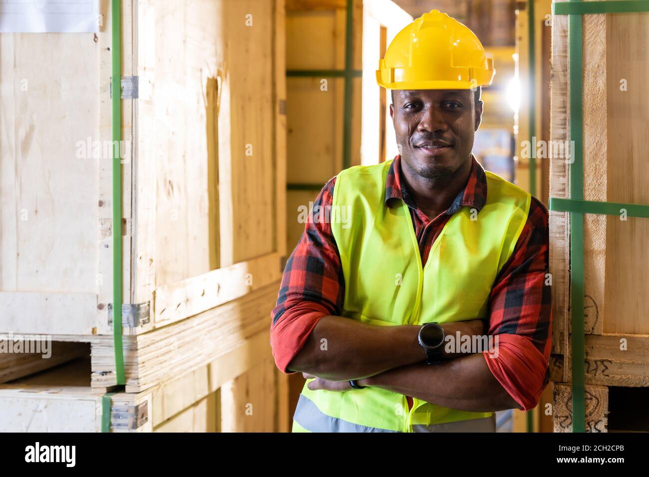 Portrait of african black warehouse worker standing and crossed his arms smile and looking at camera in large warehouse distribution center. Using in Stock Photo