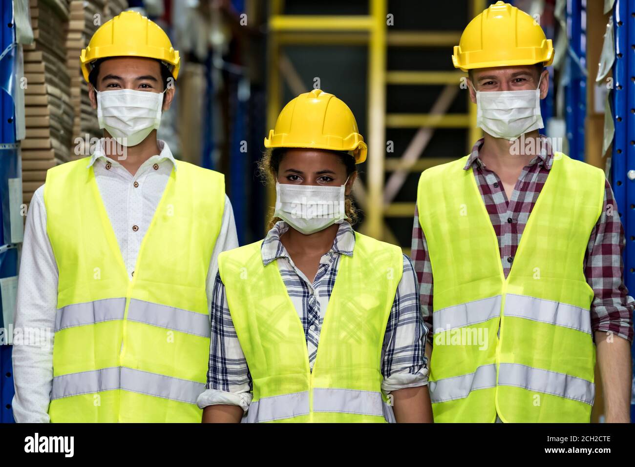 Portrait of Interracial group Asian African and Caucasian warehouse workers team wear face mask to prevent COVID-19 coronavirus infection in distribut Stock Photo