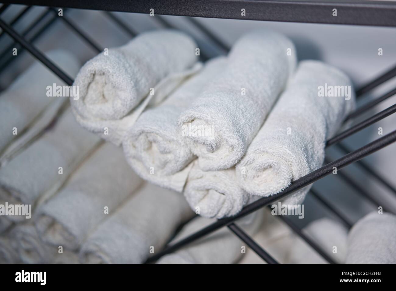 White clean towels rolled up on a roll are stored on shelves in a