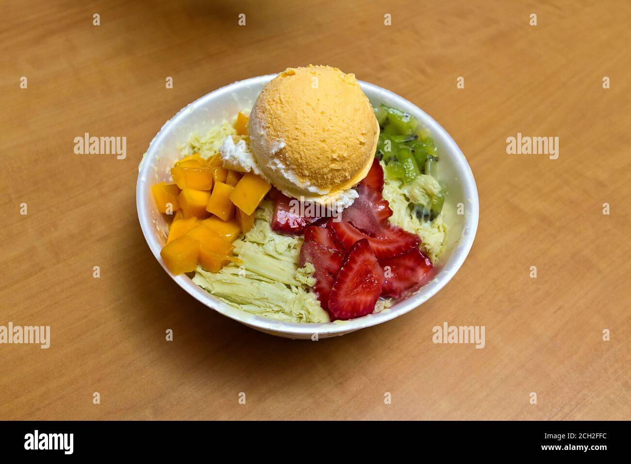 Frappe, a very popular Asian summer dish featuring flavored shaved ice with fruit and often a scoop of ice cream. This is green tea ice with mango and strawberries along with mango ice cream. Stock Photo