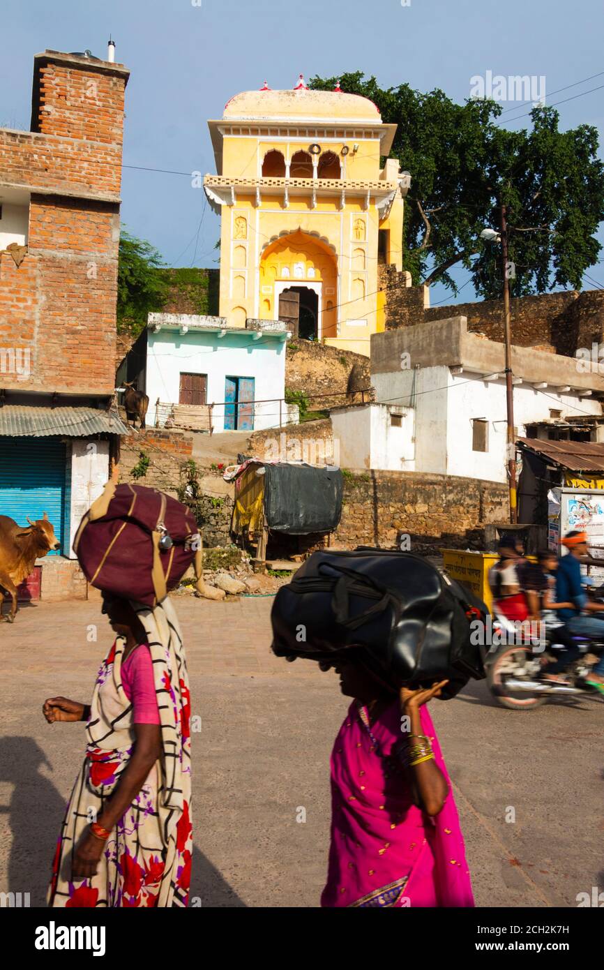 Chitrakoot, Madhya Pradesh, India : Women walk in the street carrying luggage on their heads. Stock Photo