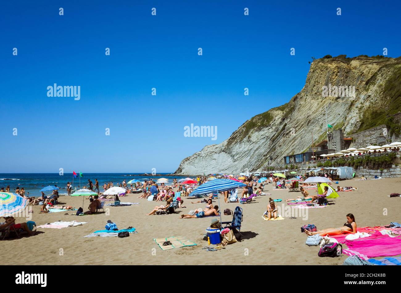 Zumaia, Gipuzkoa, Basque Country, Spain - July 15th, 2019 : Beach goers sunbath at Itzurun Beach. Stock Photo