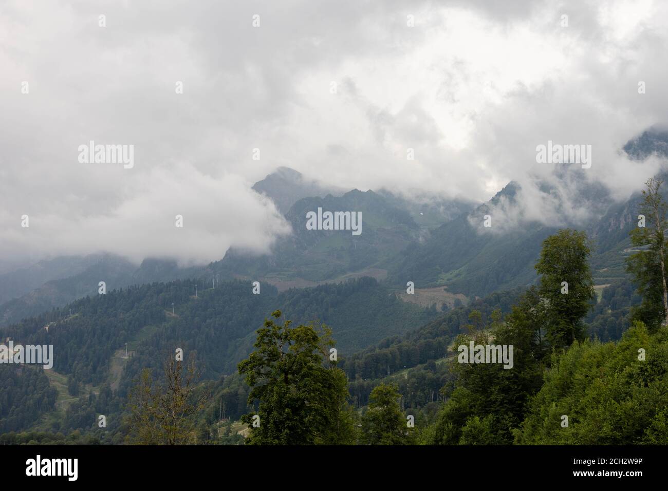 Forested mountains with clouds, ski resort in summer. Lift towers in the distance. Beautiful landscape Stock Photo