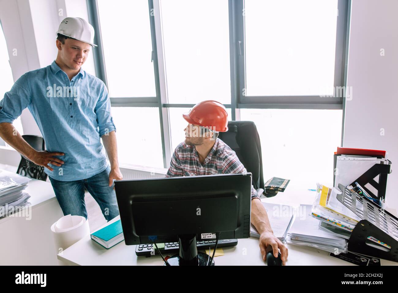 two ambitious construcors are studing the project from the computer in the office with modern interior. close up photo Stock Photo