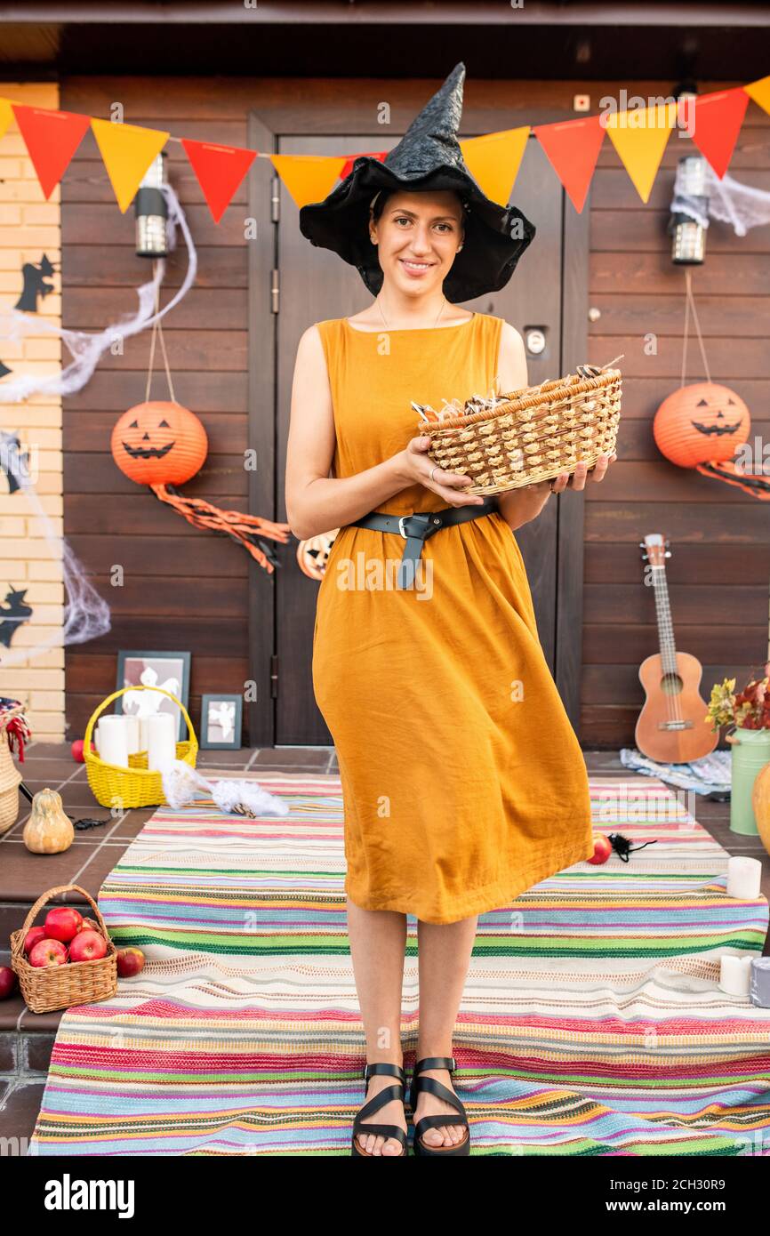 Young smiling woman in elegant dress and black hat holding basket with sweets Stock Photo