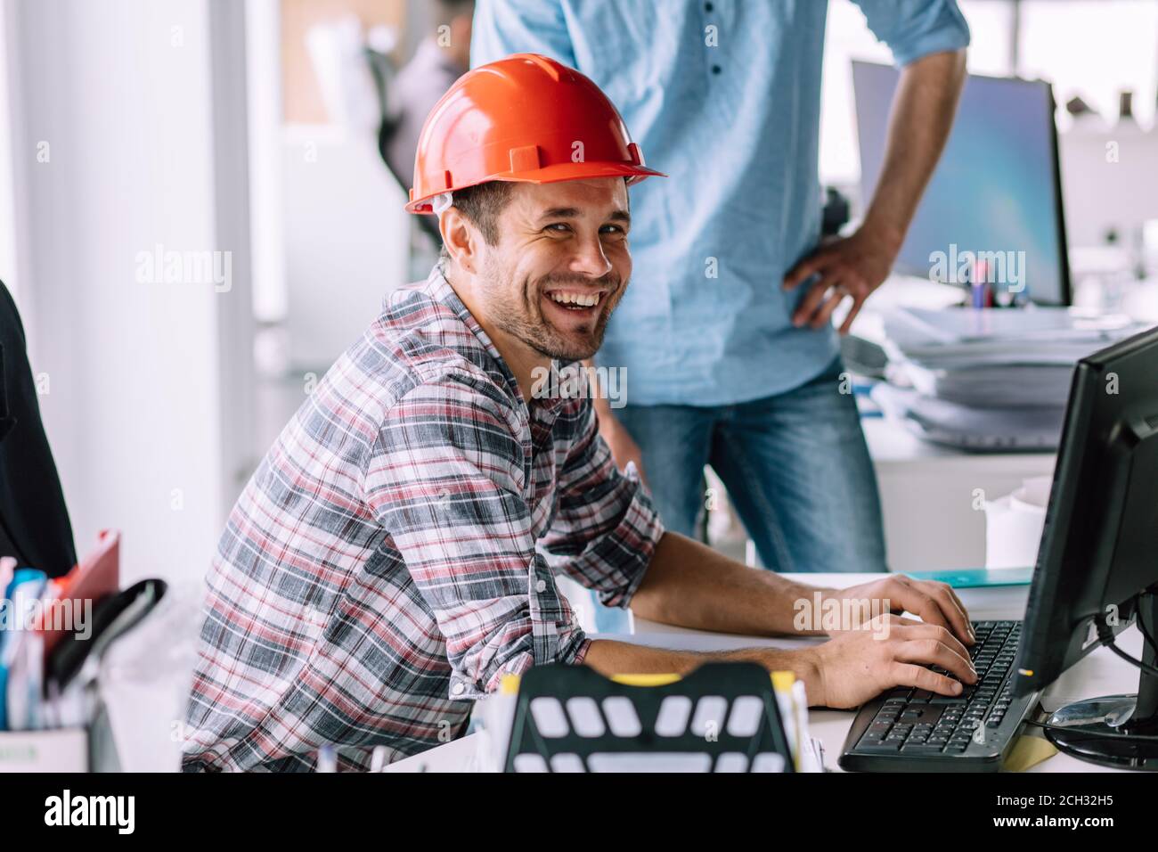 handsome cheerful engineer is having fun in front of the computer at ...