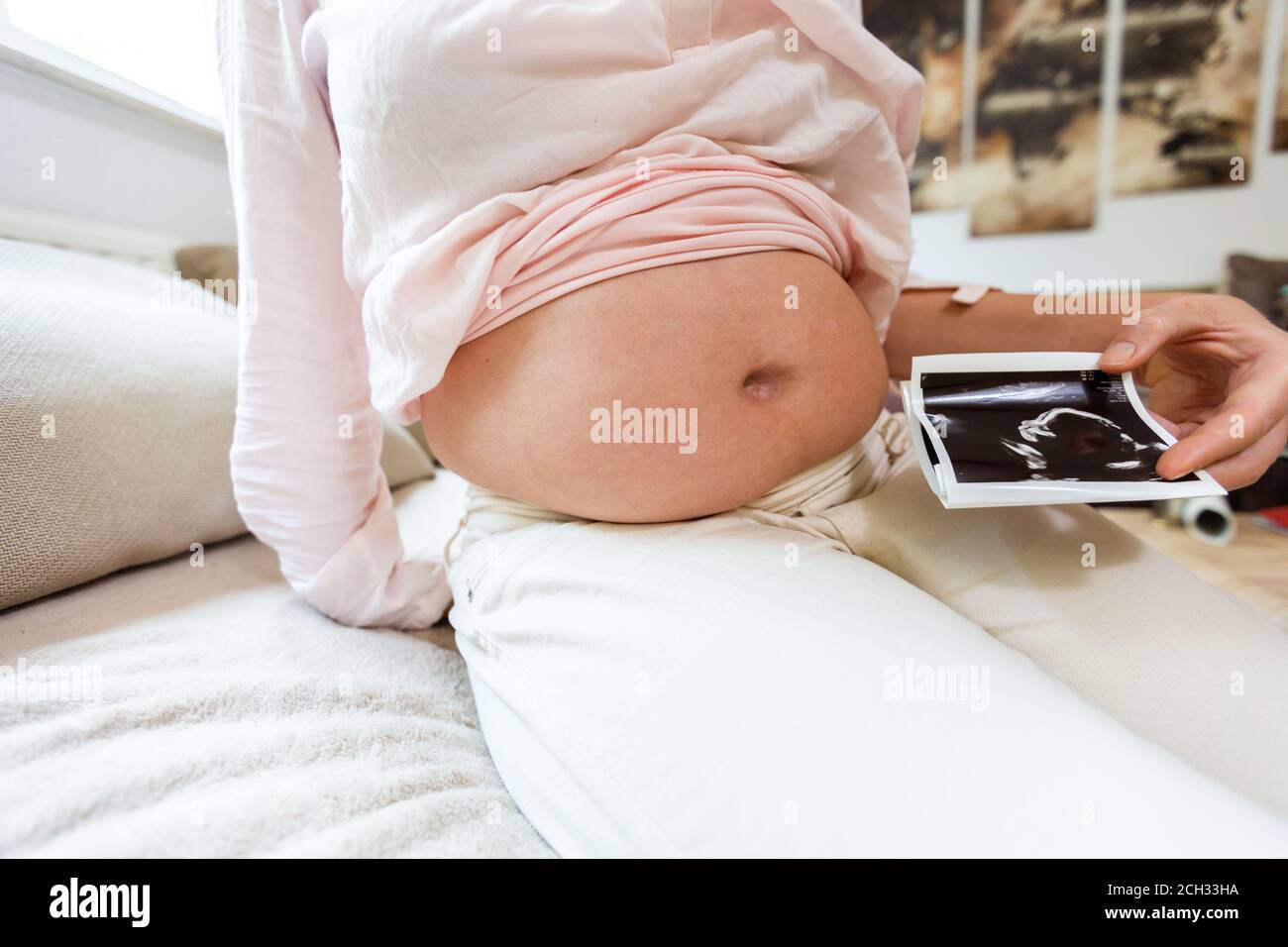 a pregnant woman holds a baby photo in front of her belly Stock Photo
