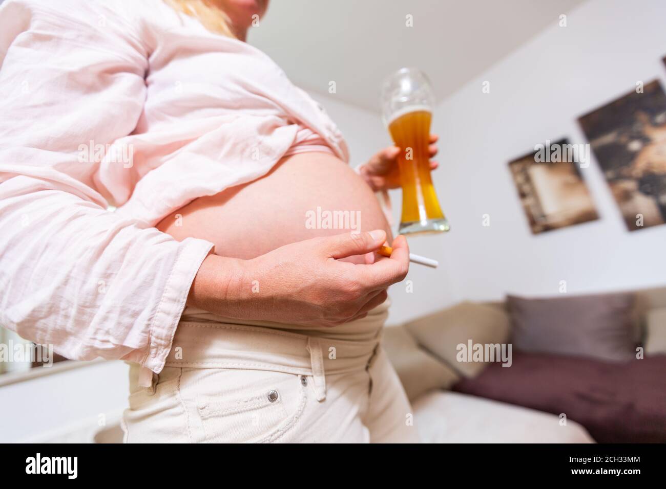 a pregnant woman with a beer and a cigarette in her hand Stock Photo