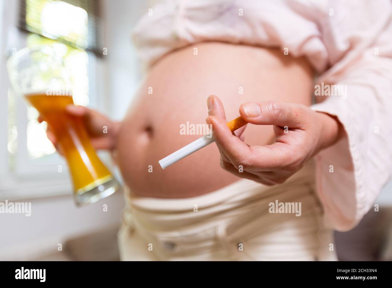 a pregnant woman with a beer and a cigarette in her hand Stock Photo