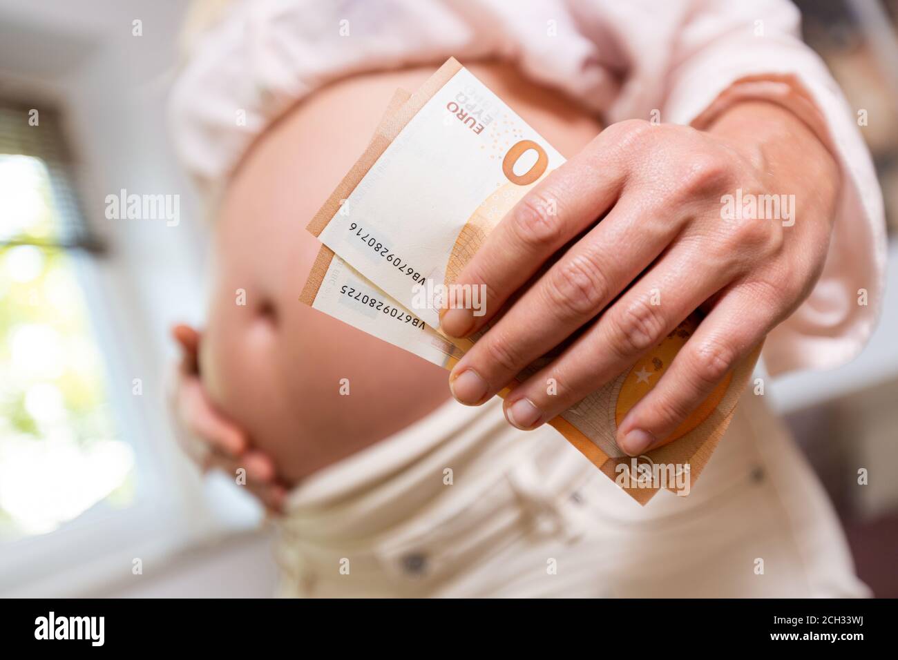 a pregnant woman holding money in her hand Stock Photo