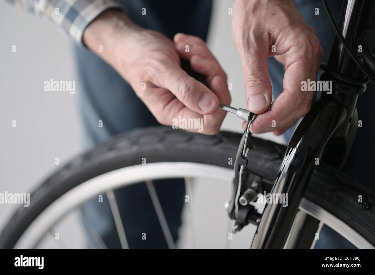 Mature Caucasian man adjusts the brake of his new bicycle indoors Stock Photo