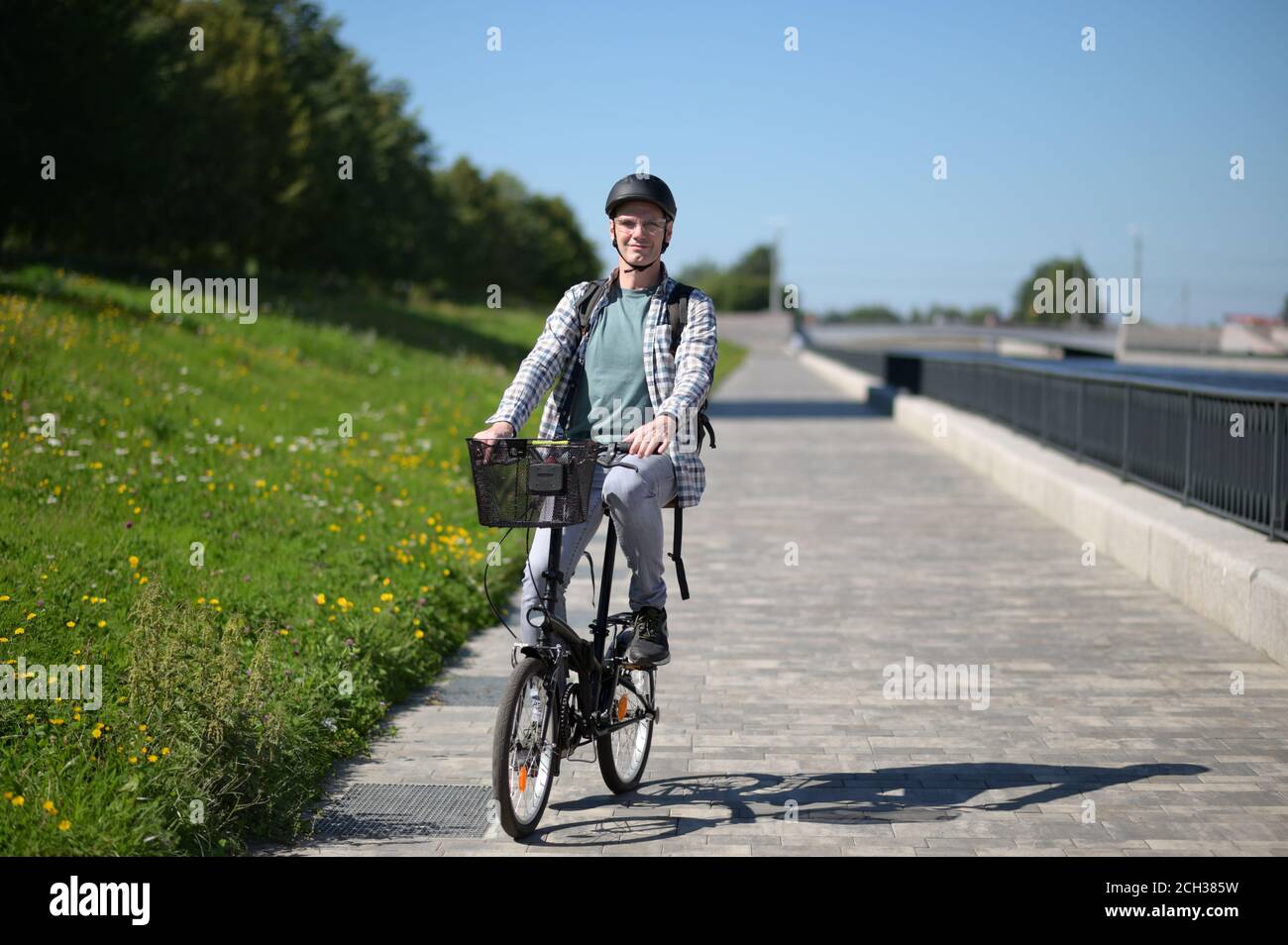 Mature Caucasian man in a bicycle helmet on his bike at a river embankment Stock Photo