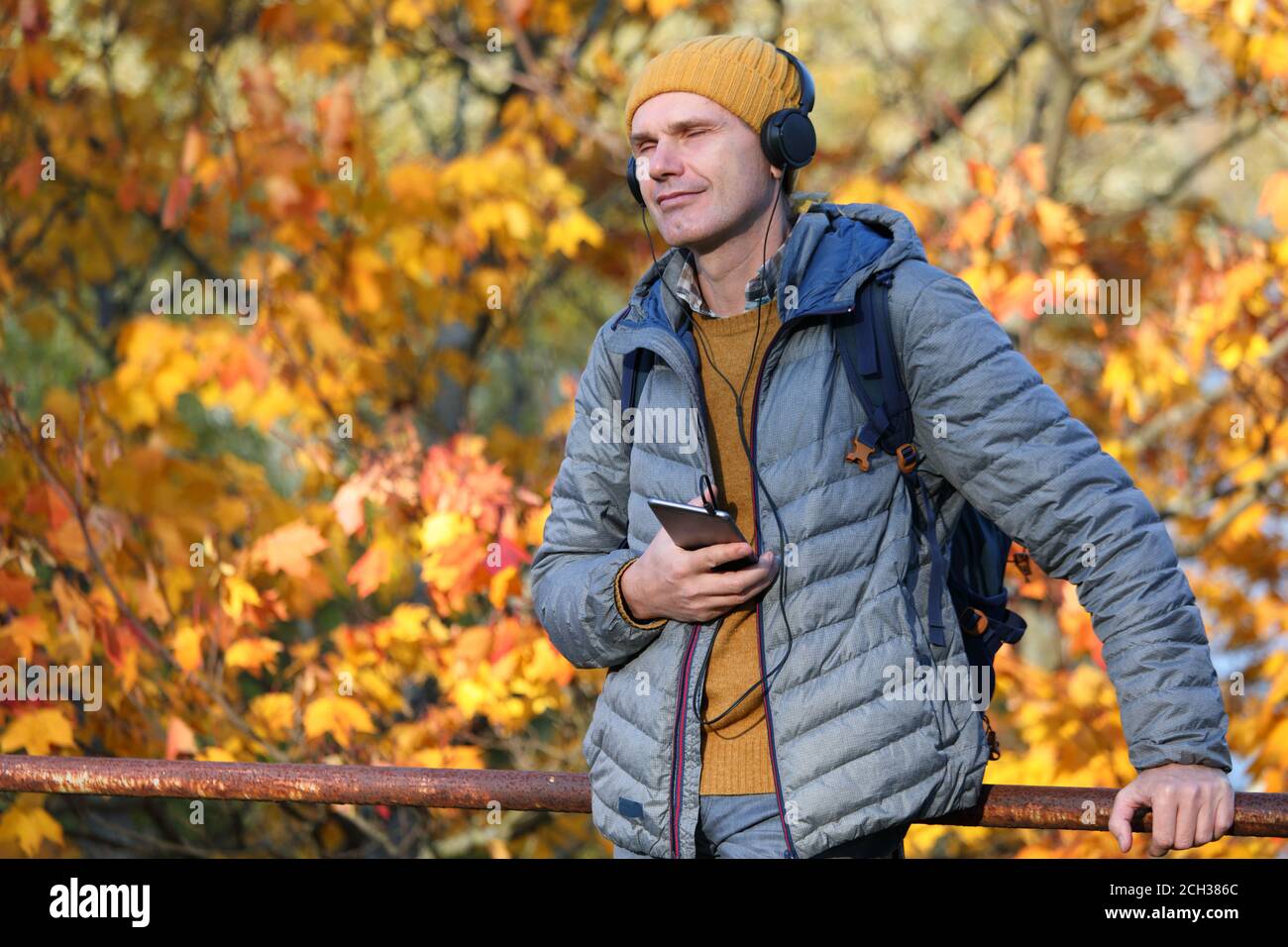 Man in headphones listening music from his smart phone outdoors in a sunny autumn day Stock Photo