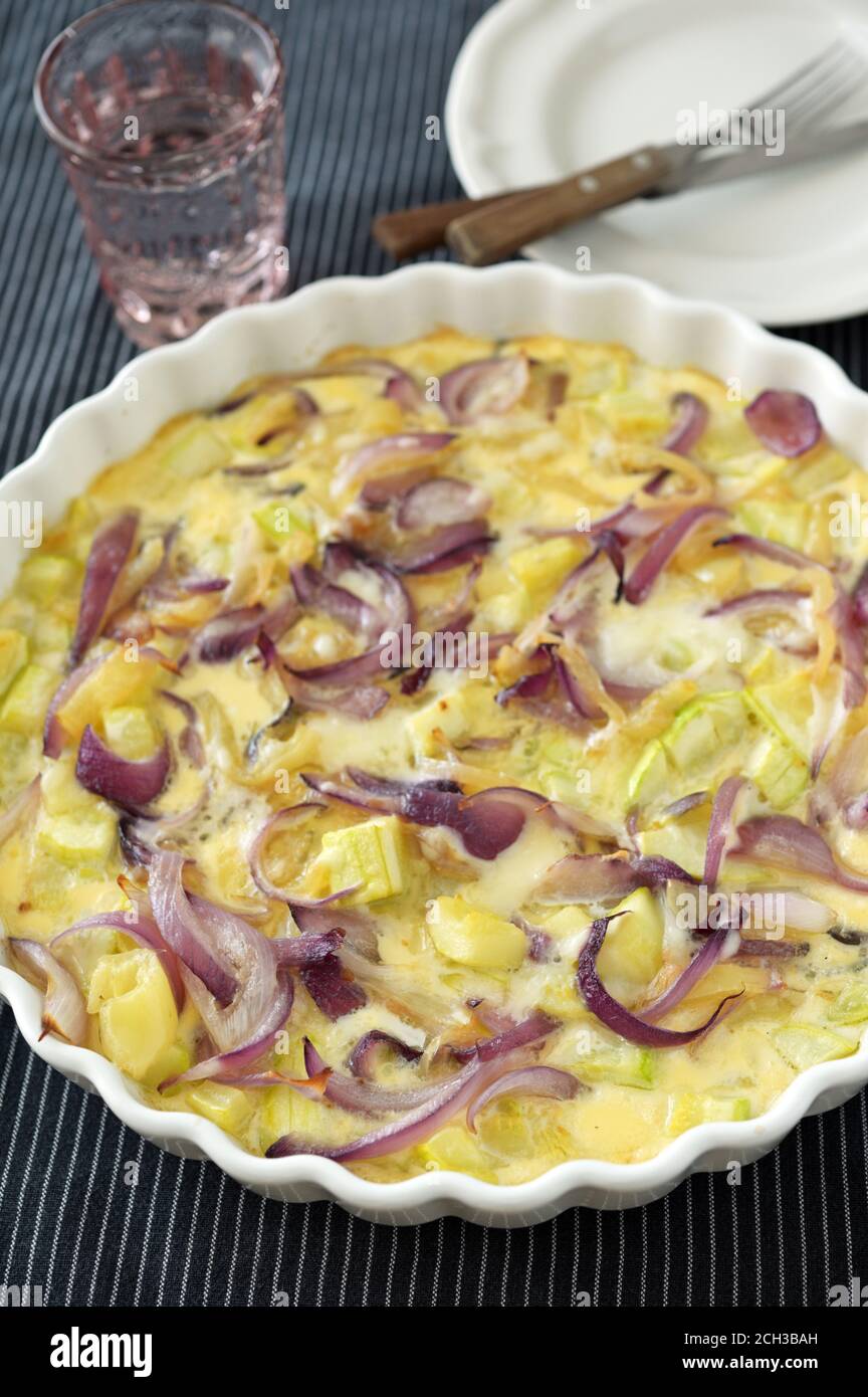 Baked omelet with summer squash and red onion in a baking dish. Selective focus on the front side of baking dish Stock Photo