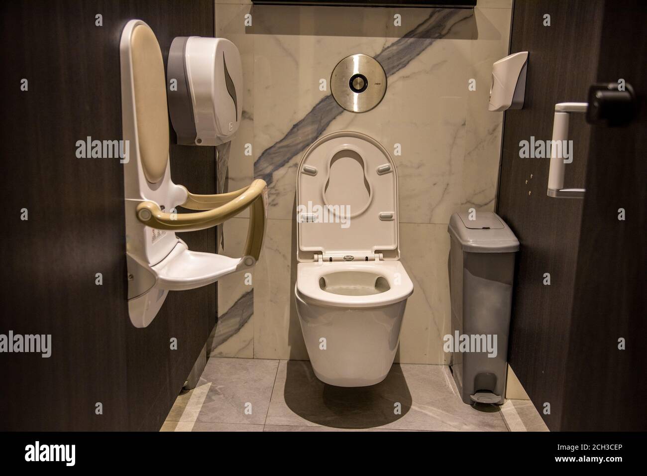 mother care publc toilet equipment. cubicle of a public toilet equipped Folding toddler safety chair mounted on wall in public restroom. friendly to Stock Photo