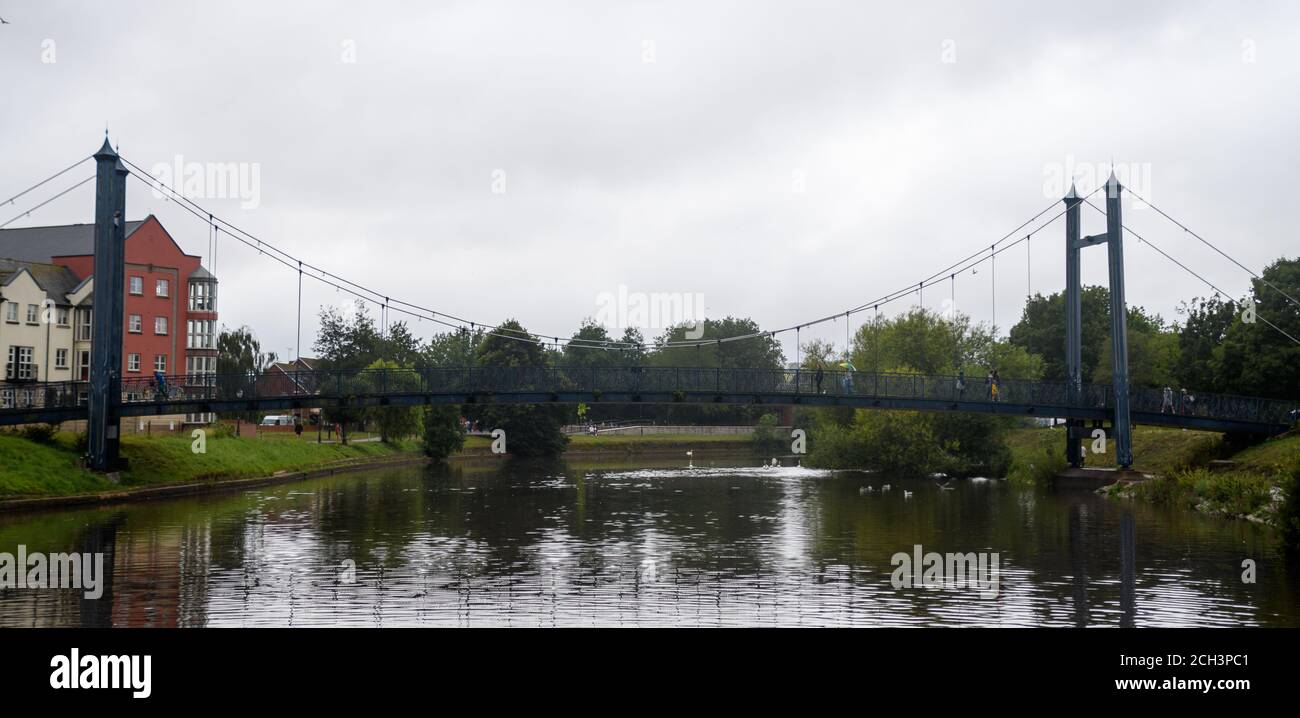 A suspension footbridge spans the waters of the river Exe at Exeter ...