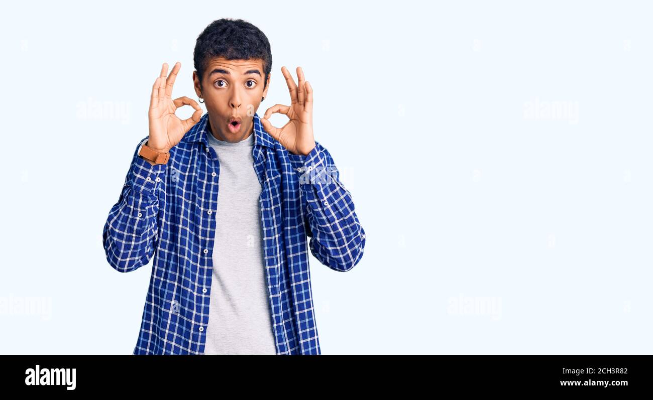 Young african amercian man wearing casual clothes looking surprised and shocked doing ok approval symbol with fingers. crazy expression Stock Photo