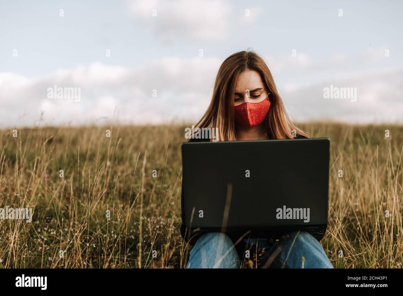 Girl with mask and laptop in nature Stock Photo
