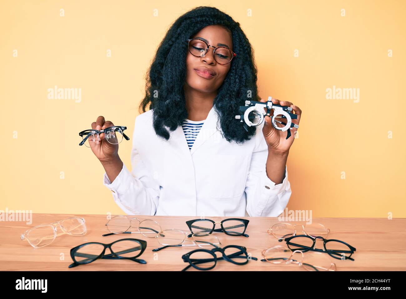 Young african american woman wearing optician uniform holding glasses
